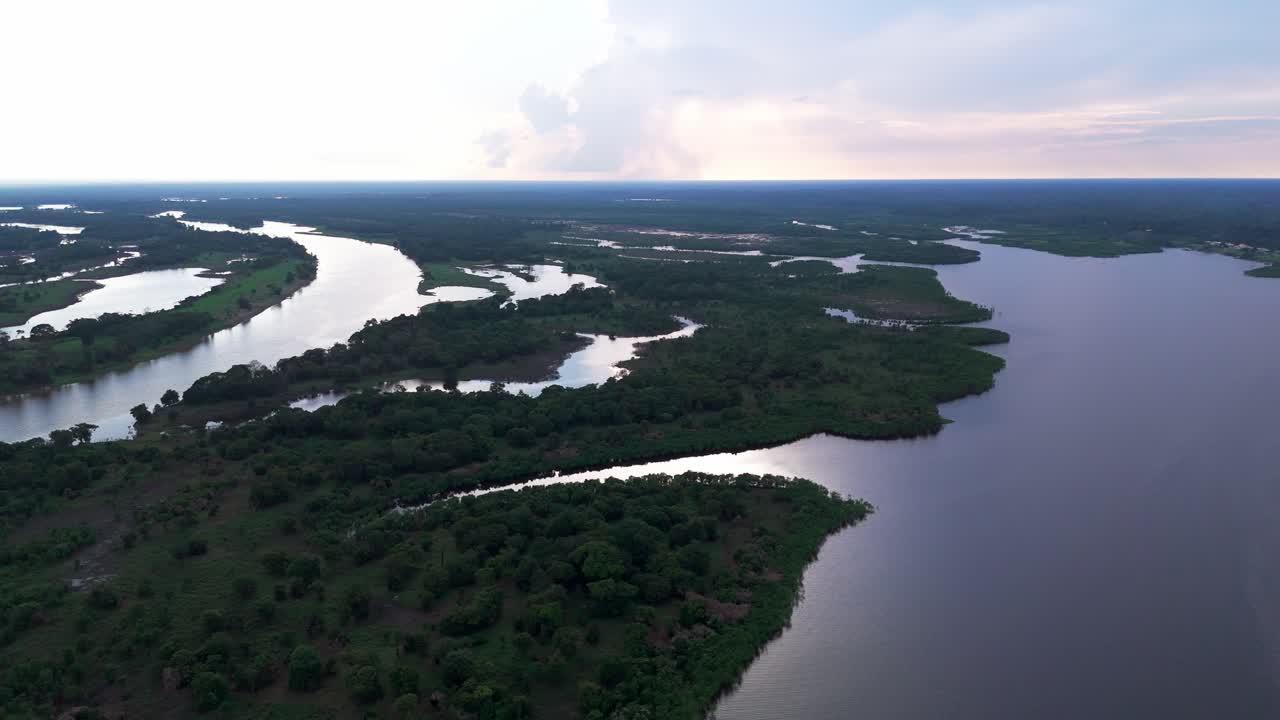 Aerial view over the Amazon River at dusk, revealing winding waterways, forested islands, and the peaceful stillness of the rainforest landscape in evening light