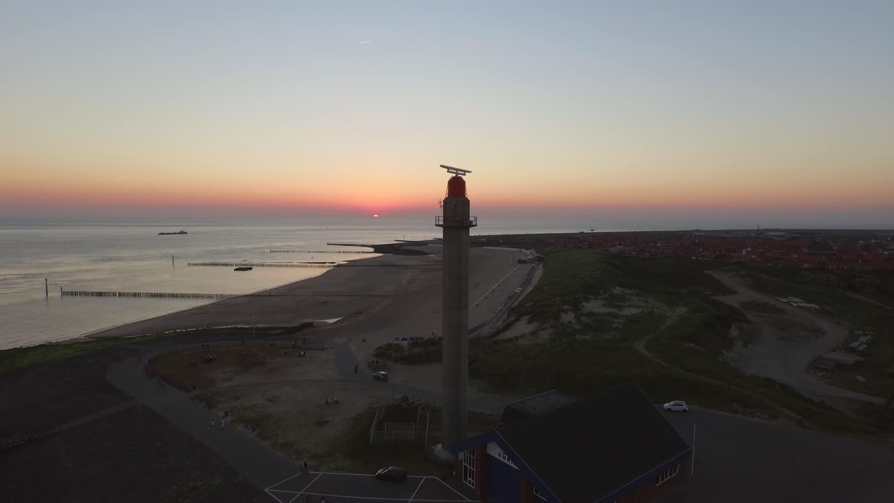 antena: el muelle, la playa y el faro durante la puesta de sol cerca del pueblo de westkapelle, países bajos