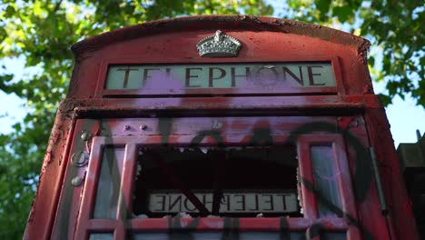 Vergrößern-Sie-Die-Aufnahme-Einer-Roten-Telefonzelle,-Zerstörte-Telefonzelle-Mit-Graffiti-Und-Zerbrochener-Brille