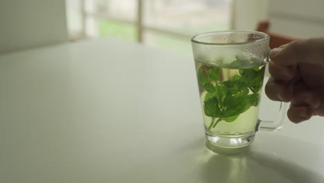 mint tea in glass is taken out and put back in frame with apartment in background