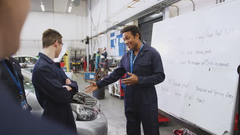 Männlicher-Nachhilfelehrer-Am-Whiteboard-Mit-Studenten,-Die-An-Der-Hochschule-Eine-Kfz-Mechaniker-Ausbildung-Unterrichten