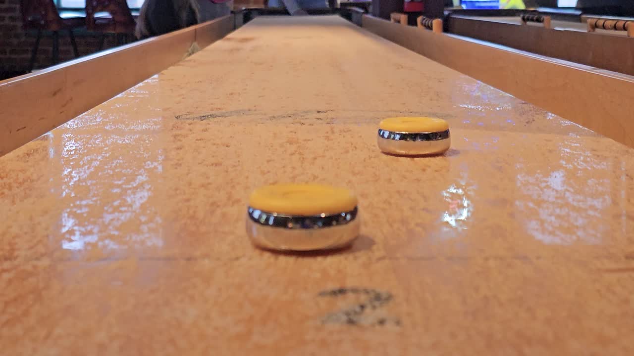 persone che giocano a shuffleboard viste da vicino al tavolo alla fine