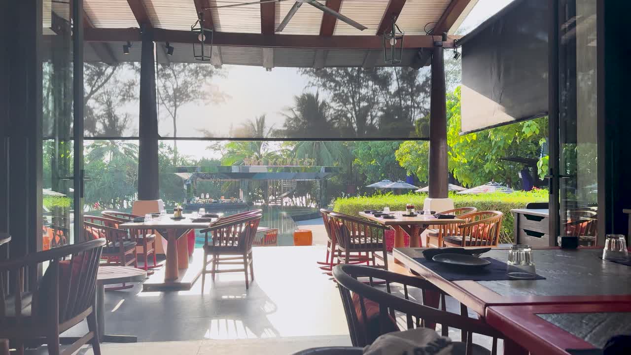 Empty dining area with natural light and lush greenery, creating a tranquil atmosphere at a luxury resort in Phuket, Thailand