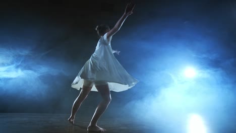 woman in white dress on stage with smoke dancing modern ballet.