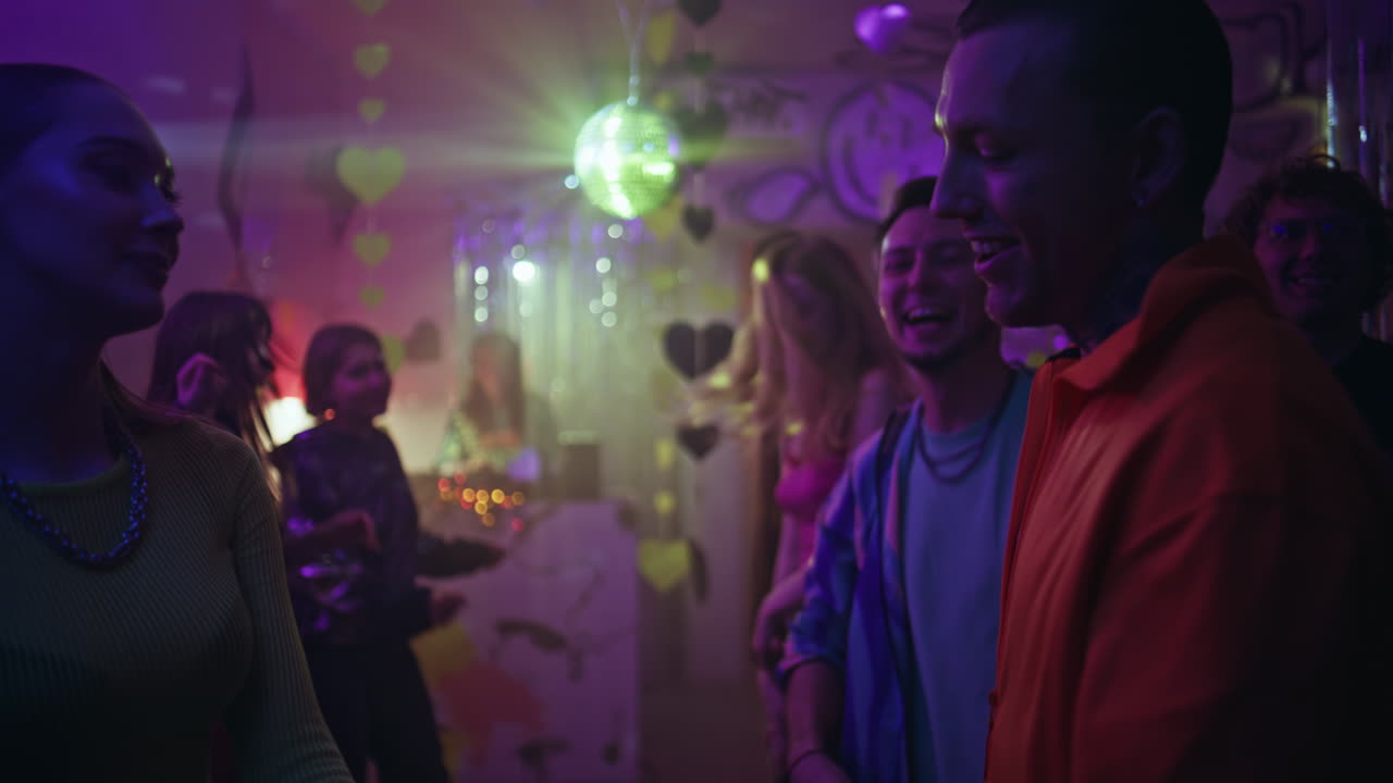 Party people enjoy club celebration with neon lights. Excited crowd dancing