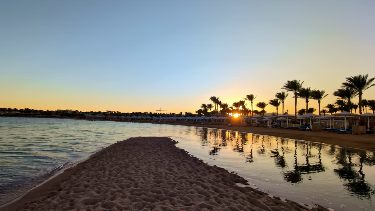 Ombrelloni da spiaggia e palme sulla spiaggia al tramonto.