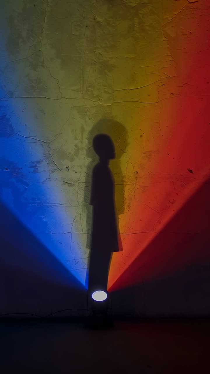 Vídeo vertical: Fazendo sombra, ela de casaco inclinando-se e retornando sob iluminação LED tricolor projetada na parede.