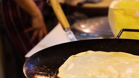 el vendedor prepara roti con huevo y plátano