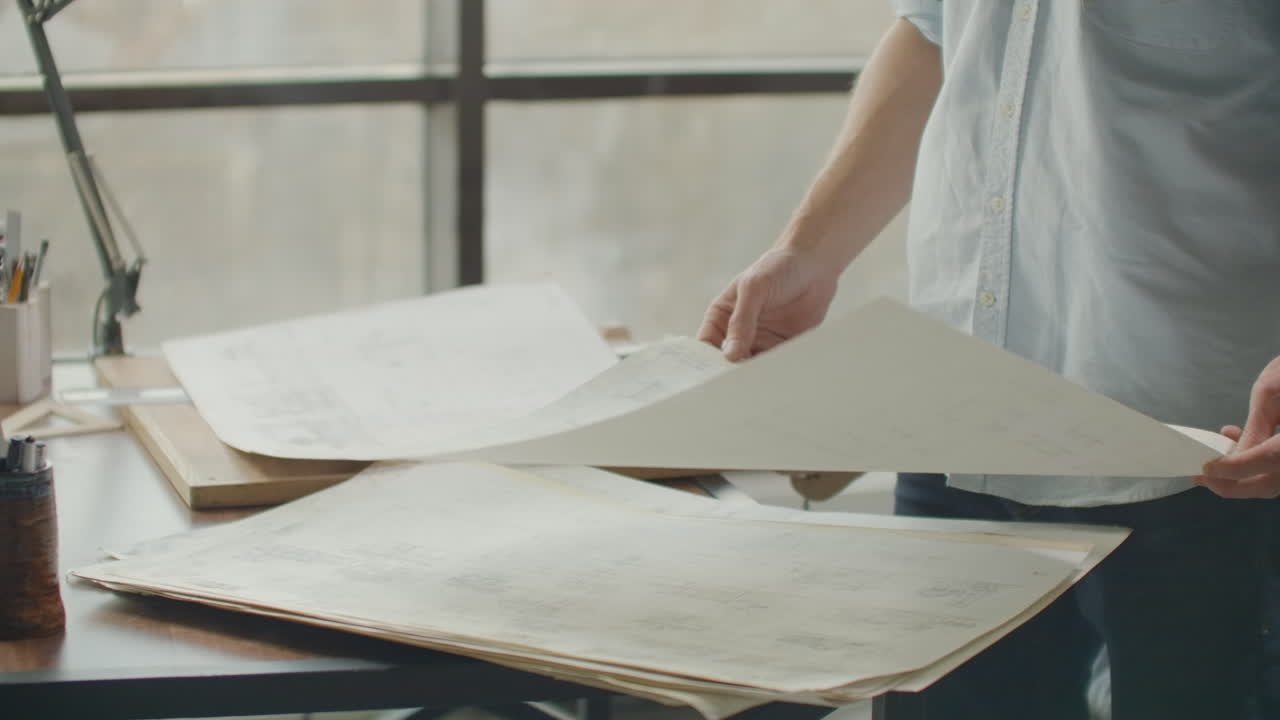 엔지니어는 넓은 창문이 있는 밝은 사무실에서 일하며, 계획을 세우고 그려낸다. 건축가나 디자이너의 작업장: 로프트 스타일의 미니멀한 인테리어 그림과 테이블 위의 커피.