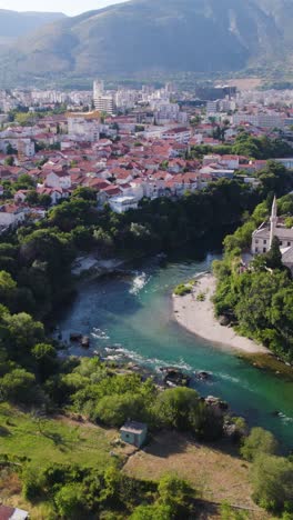 mostar with river, red rooftops and mosque in a peaceful setting, aerial vertical view