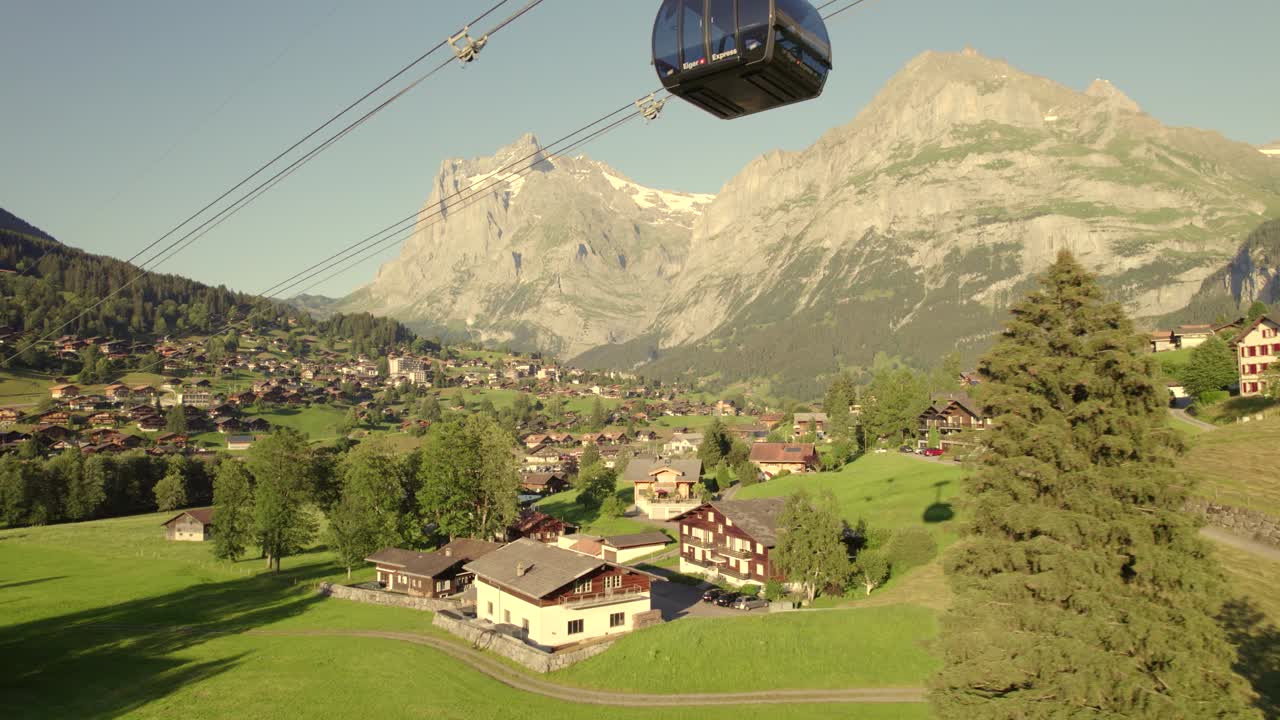 dolly de izquierda a derecha siguiendo una cabina ascendente del sistema de tricable eiger express en grindelwald, frente al monte wetterhorn y mettenberg