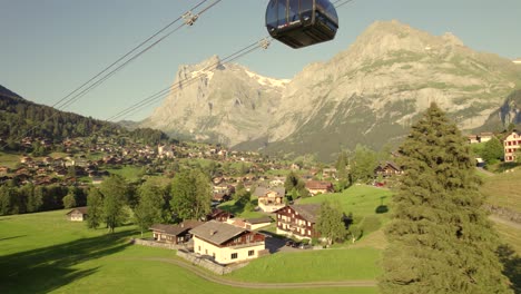 dolly-left-to-right-following-an-ascending-cabin-of-tricable-car-system-Eiger-Express-in-Grindelwald,-in-front-of-Mount-Wetterhorn-and-Mettenberg