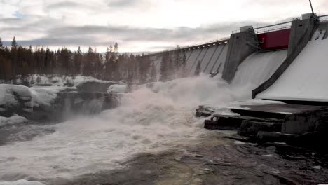 river dam iced discharge in the middle of frozen forest - low angle fly through shot