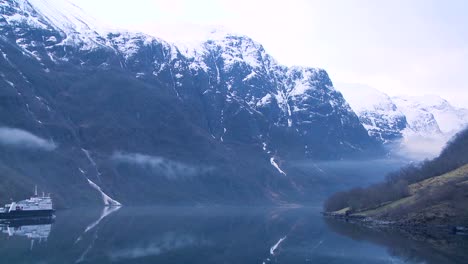 a ferry boat sails into the fog of a norway fjord