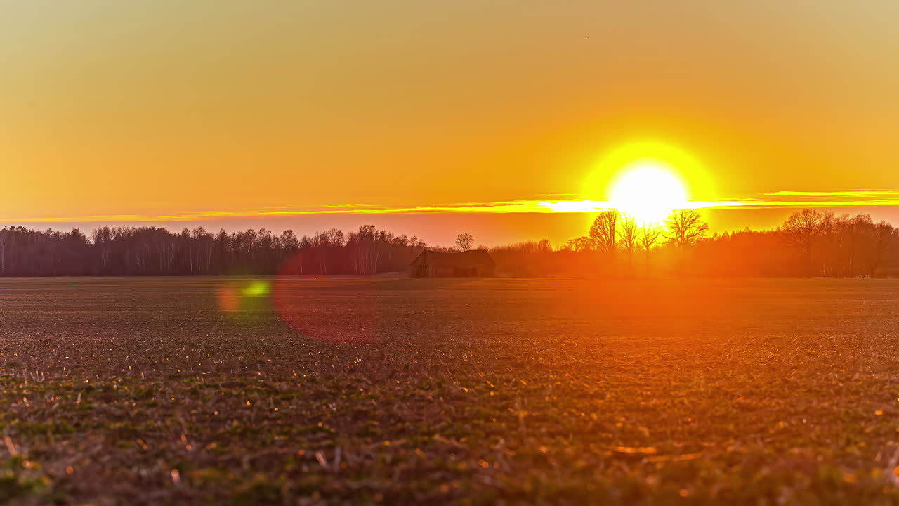 puesta de sol brillante en el paisaje rural con silueta de granero, lapso de tiempo de fusión