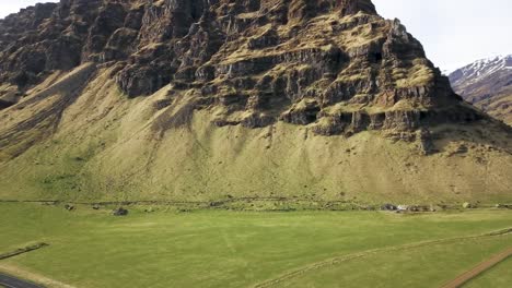 iceland farm fields with jagged rocky mountain off of ring road