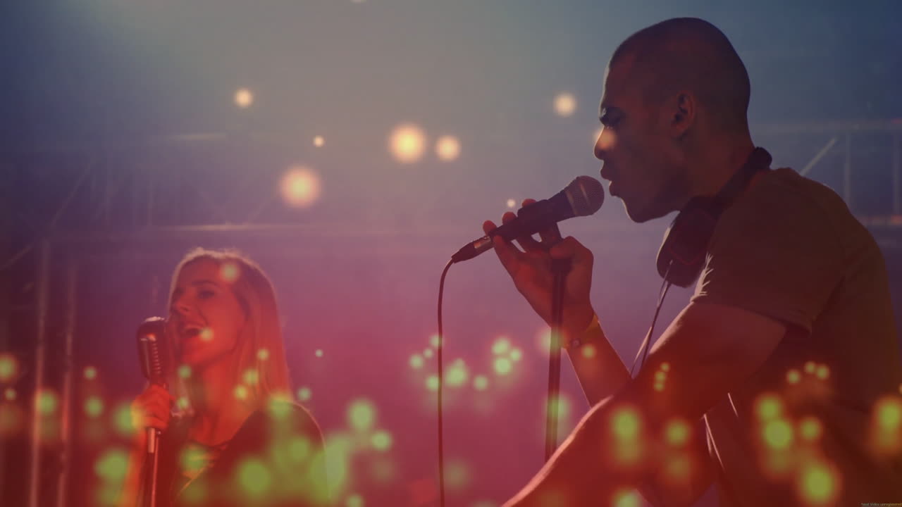 Duo performing on music stage under colored spotlights, with animated equalizers around microphones