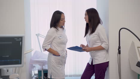 female doctor and nurse with a clipboard talking about medical diagnosis and treatment in the hospital