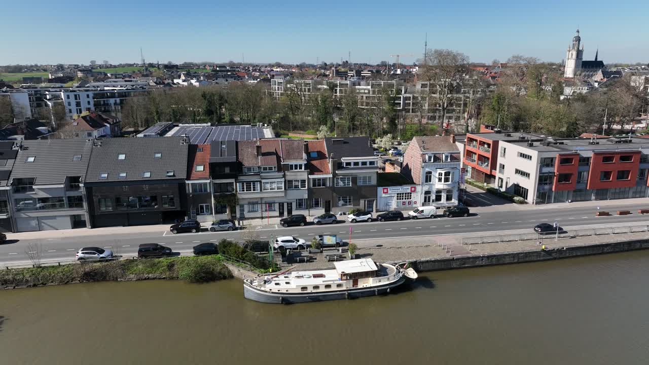 Semi orbit zoom in aerial shot of a boat docked by canal with urban houses and skyline of Brussels, Belgium