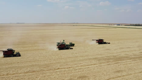 aerial parallax around combines harvesting grain in saskatchewan, canada