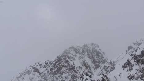 aerial view over a rocky ridge towards dark cloudy, snowstorm sky - rising, drone shot