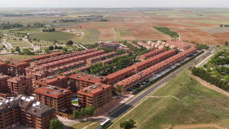 Modern-living-district-in-Spain-with-public-bus-speeding-by,-aerial-zoom-in-view