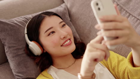 happy woman, headphones and phone in a living room