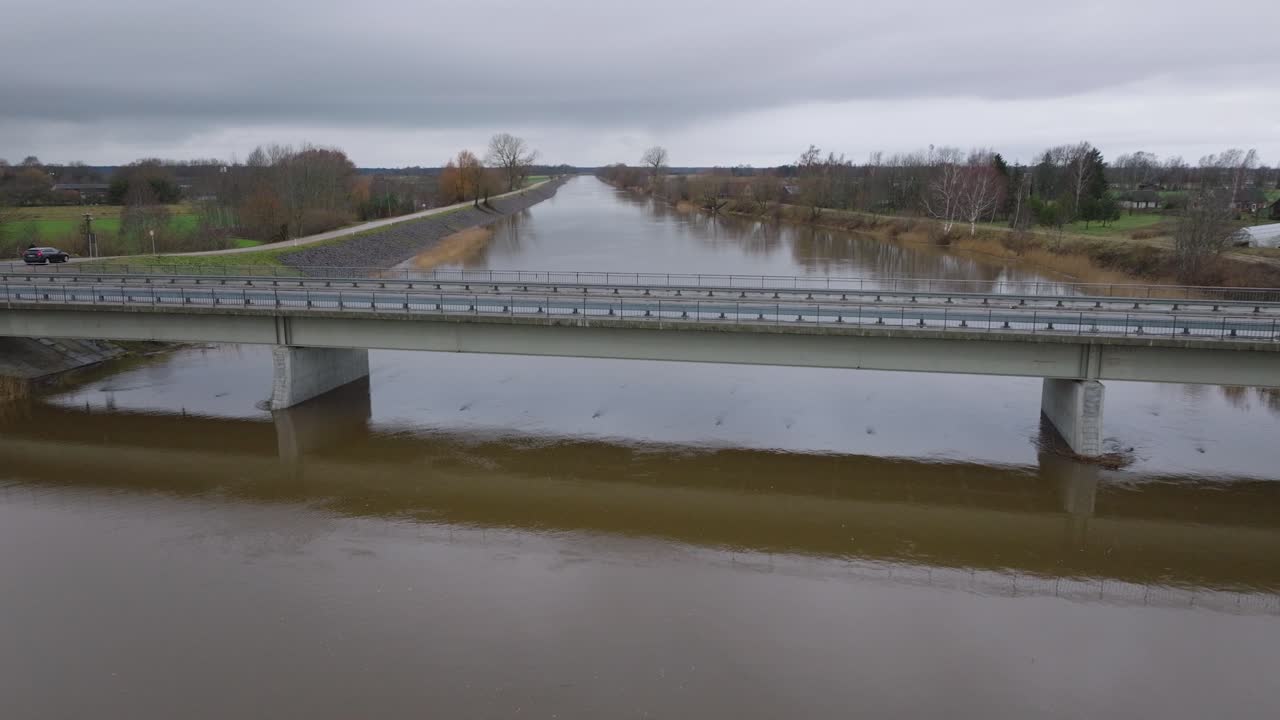 봄의 높은 물, 바르타 강 홍수, 갈색과 진 물, 흐린 날, 다리 위로 나아가는 넓은 드론