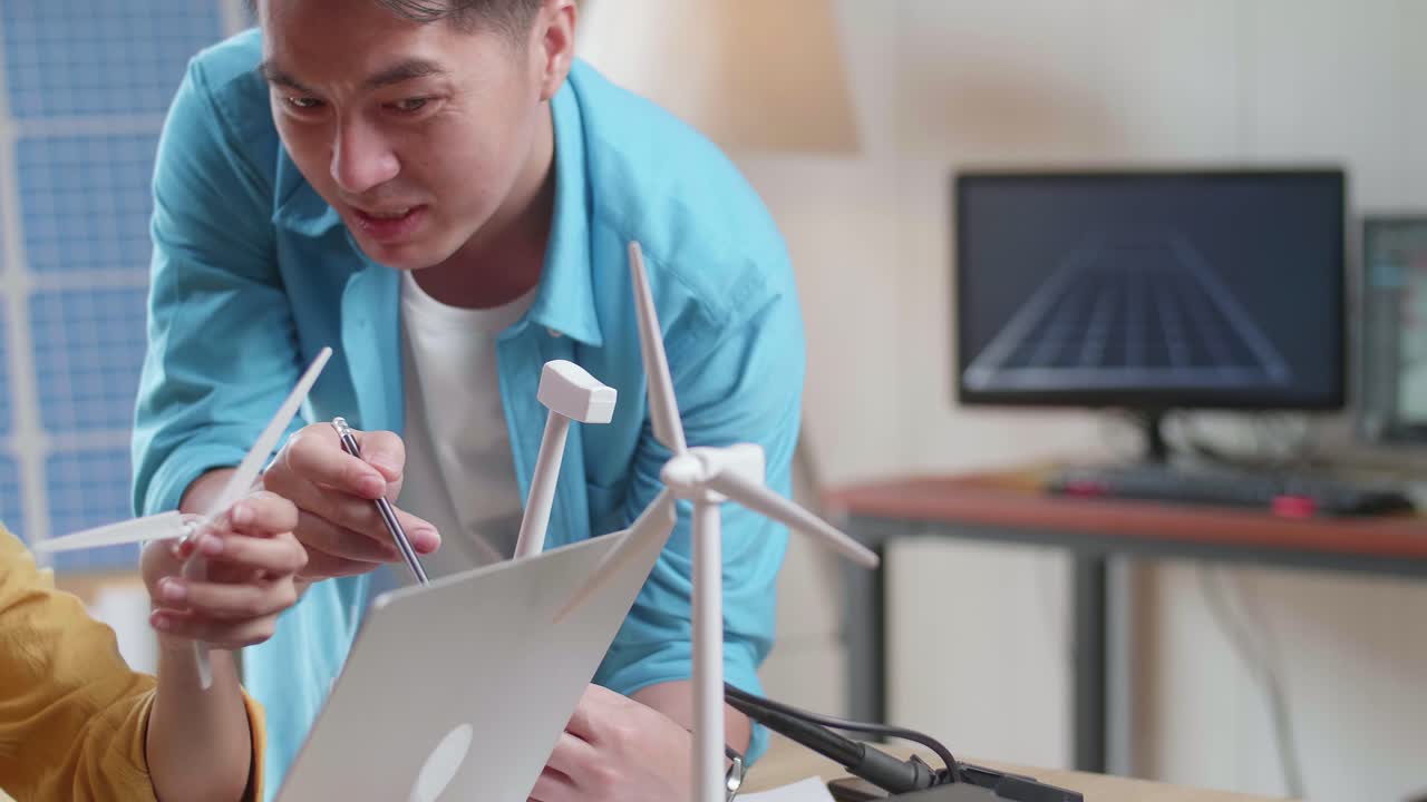 아시아 남녀가 사무실에서 태양전지 에 노트북으로 작업하는 동안 풍력 터빈을 조립합니다.