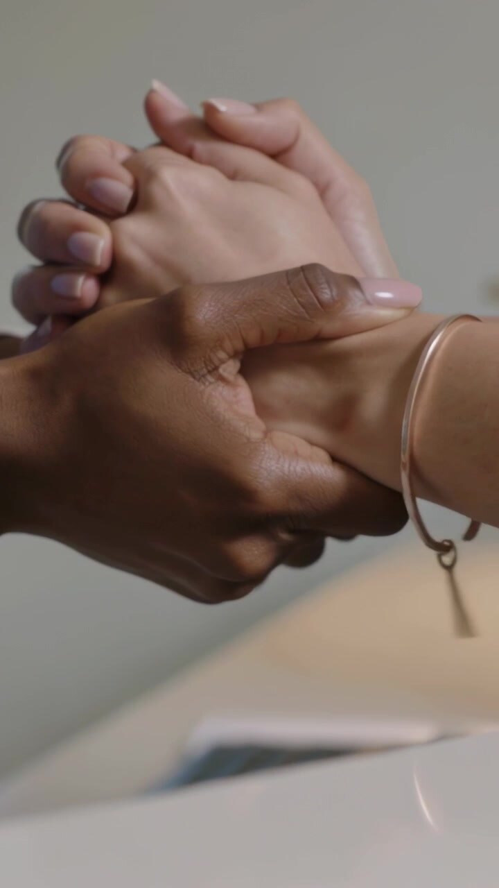 Video vertical: Mano más oscura extendiéndose y agarrando una mano más clara en la cocina, brindando apoyo con un llavero