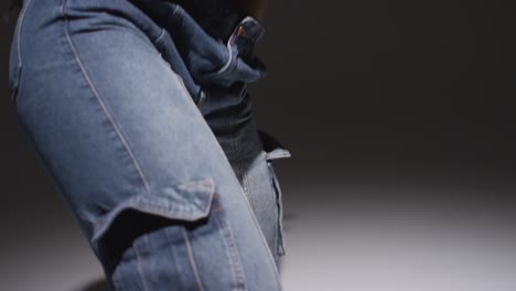 studio portrait shot of young woman wearing hoodie dancing with low key lighting against black background 4