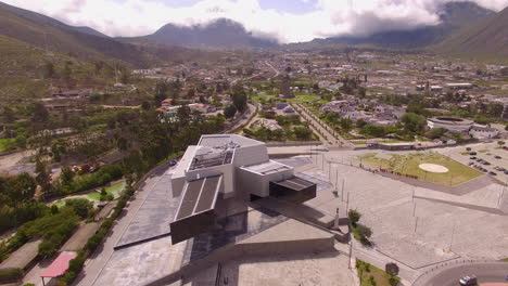 fly over a large modern building in the city of mitad del mundo in ecuador