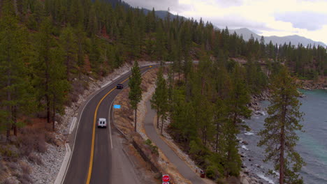 cars driving away on road winding past lake tahoe in reno, nevada on a cloudy winter day