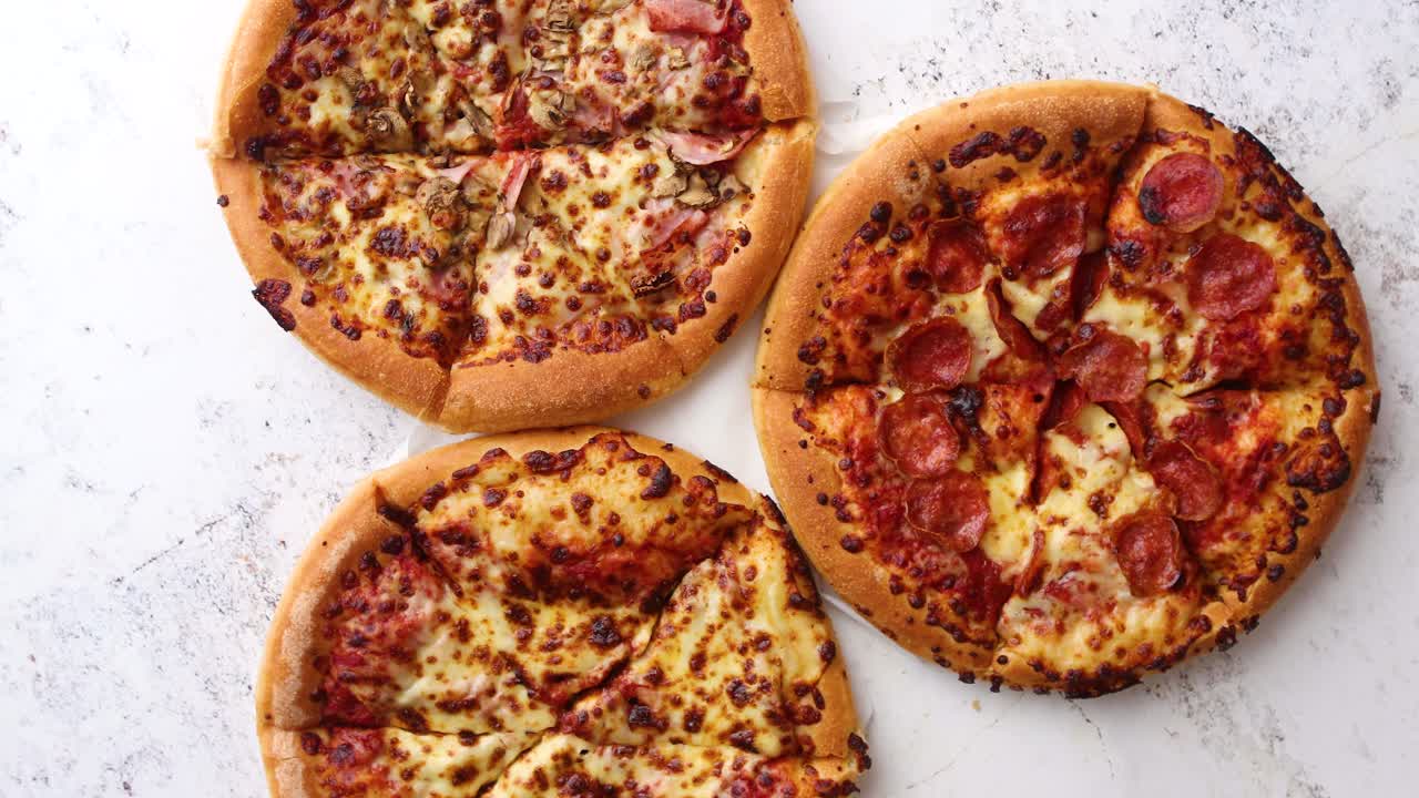 아메리칸 스타일 피자 3개가 테이블에 제공됩니다.