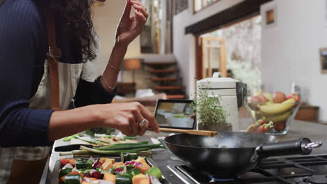 midsection of biracial woman preparing and tasting meal in kitchen, slow motion