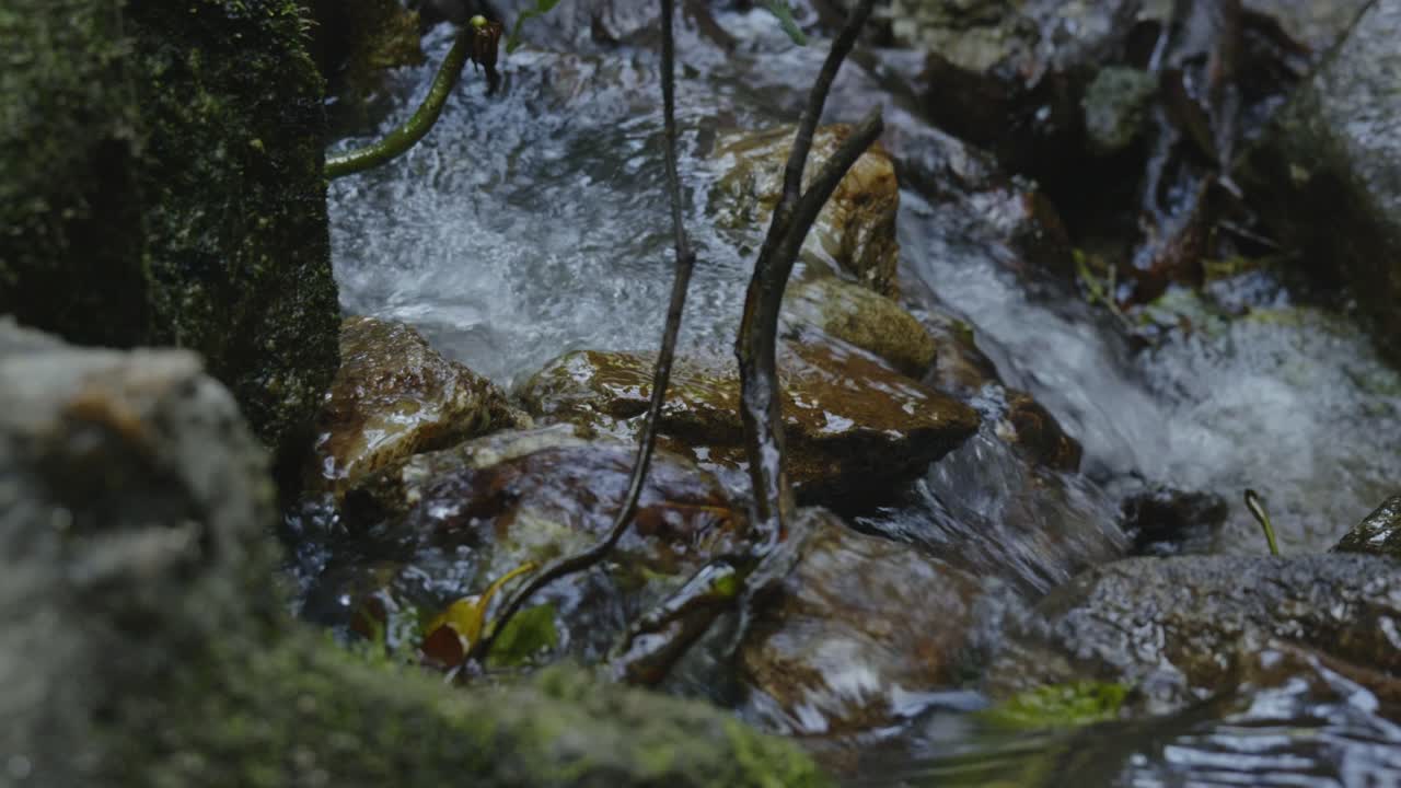 A mesmerizing view of water gracefully flowing through rocks, creating rippling patterns in a serene natural setting. This tranquil scene highlights the beauty of ecosystems and conservation.