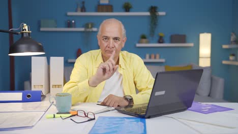 home office worker old man looking at camera with a stern angry warning.