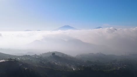 aerial view of countryside on the mountain slope with view sea of clouds and mountain range - rural landscape of indonesia