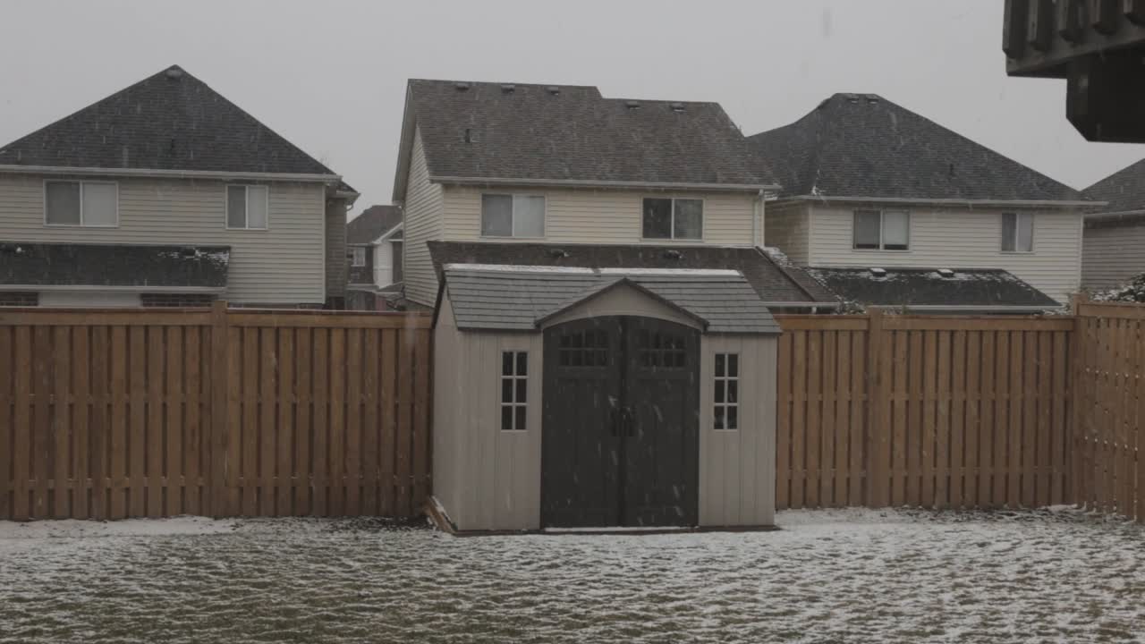 Crane shot moving upwards showing a residential backyard during a winter snowfall