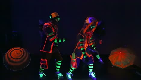 bailarines que brillan en la oscuridad con paraguas