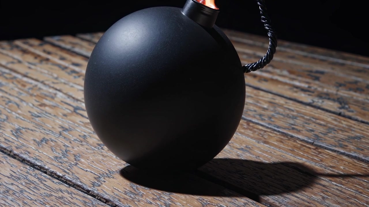 Black Round Bomb with Lit Fuse on Wooden Table