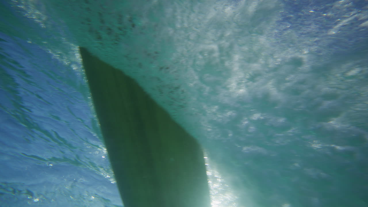 Surfer riding on a wave in crystal clear water in Byron Bay Australia shot from underwater in slow motion