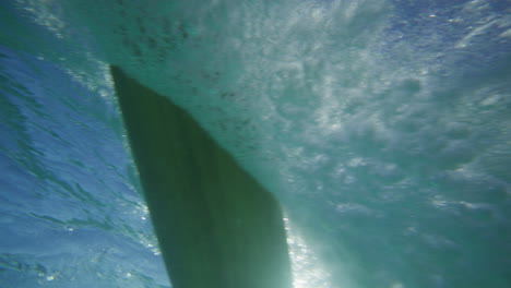 Surfer-riding-on-a-wave-in-crystal-clear-water-in-Byron-Bay-Australia-shot-from-underwater-in-slow-motion