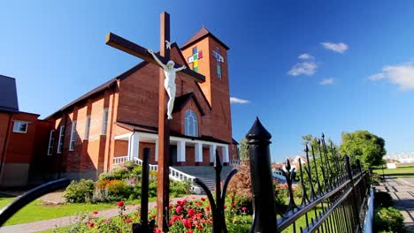 jesus on cross in church yard. exterior of modern catholic church