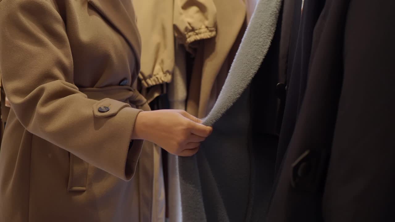 Woman's Hand Touching Soft Coat on Clothing Rack in Store