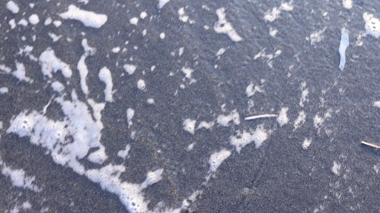 Ocean Foam Receding on Dark Sand
