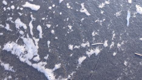 ocean foam receding on dark sand