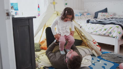 single father playing with daughter in den in bedroom at home