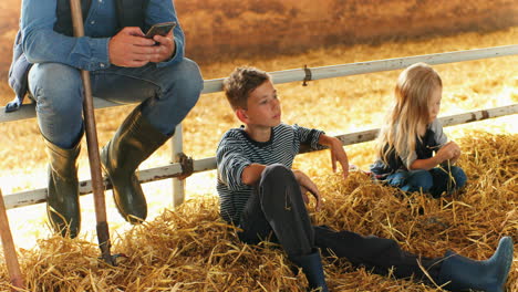 Caucasian-man-and-his-sons-sitting-and-resting-in-stable