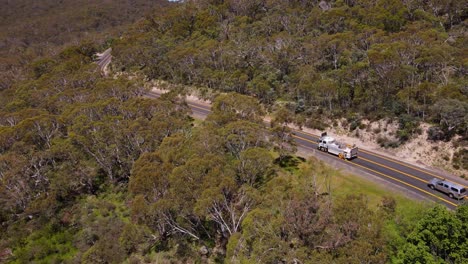 Schwenk-Drohnenaufnahme-Eines-Vorbeifahrenden-Lastwagens-Auf-Einer-Alpenstraße-In-Der-Gegend-Von-Crackenback,-Australien